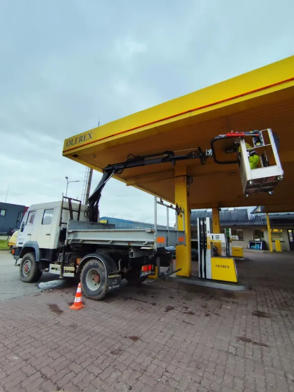 Kraanaauto tõstukorv Olerexi tankla kollase katusealuse all